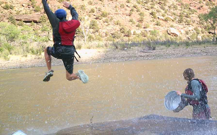 A person is mid-jump into a body of water.